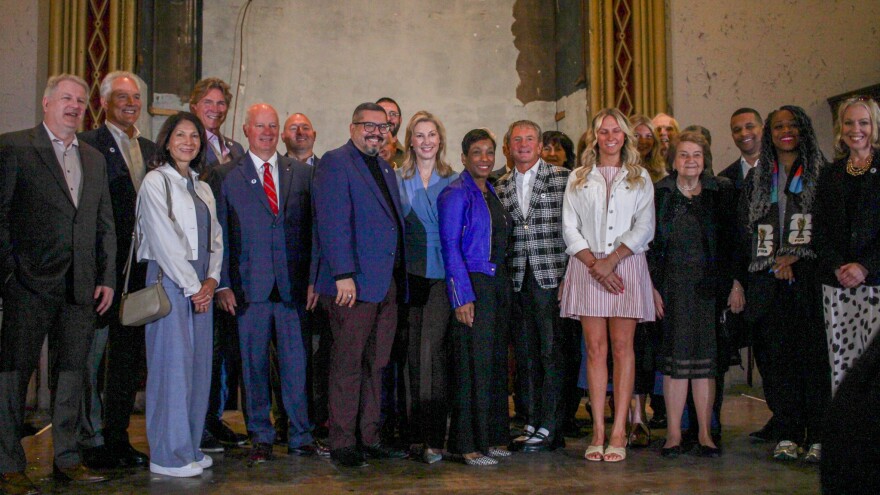 A group of well-dressed people pose for a photo on a stage in an old church. 