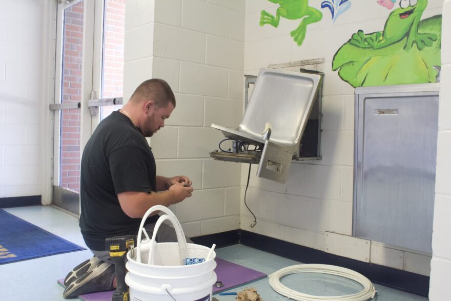 Allen Shumpert, a plumber with the Alachua County Public Schools facilities department, installs a Omnipure K5615-KK water filter in a water fountain at Metcalfe Elementary School. Filter installation takes about 20 minutes to perform, according to Shumpert. (Angel Kennedy/WUFT News)