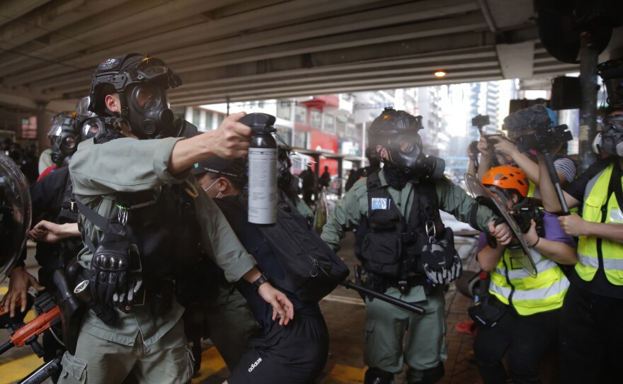 Riot Police use pepper spray on protesters during a protest against Beijing's national security legislation in Causeway Bay in Hong Kong, Sunday. Hong Kong police fired volleys of tear gas in a popular shopping district as hundreds took to the streets Sunday to march against China's proposed tough national security legislation for the city.