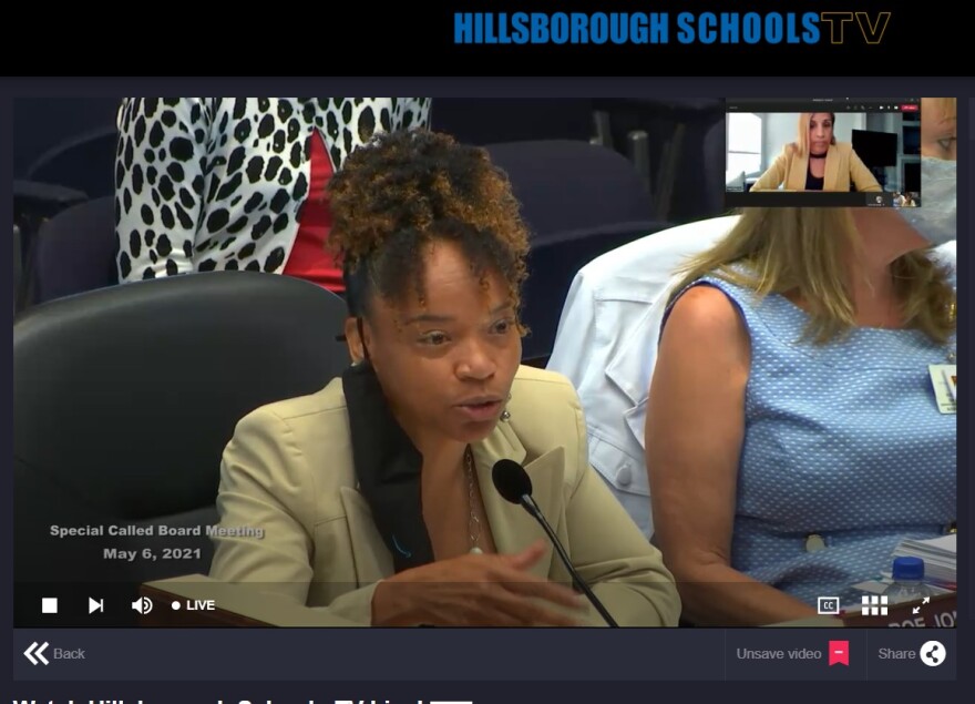CFO Romaneir Johnson speaks at a microphone wearing a tan business suit