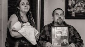 Kimberly Chavez holds her newborn as Vincent Chavez Sr. shows photos of their missing teenage son.