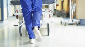 A medical professional is pushing a cart of supplies through a hospital hallway.