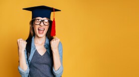 graduate wearing a cap balls fists and yells "Yay!"