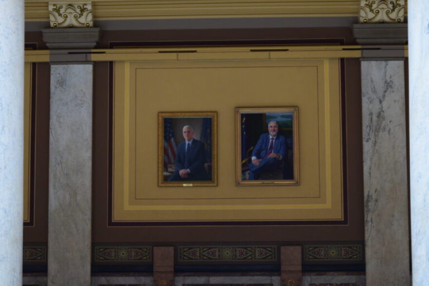 Portraits of former Govs. Mike Pence, left, and Eric Holcomb hang in a second floor public hallway at the Indiana Statehouse, where a new display of gubernatorial portraits is taking shape.