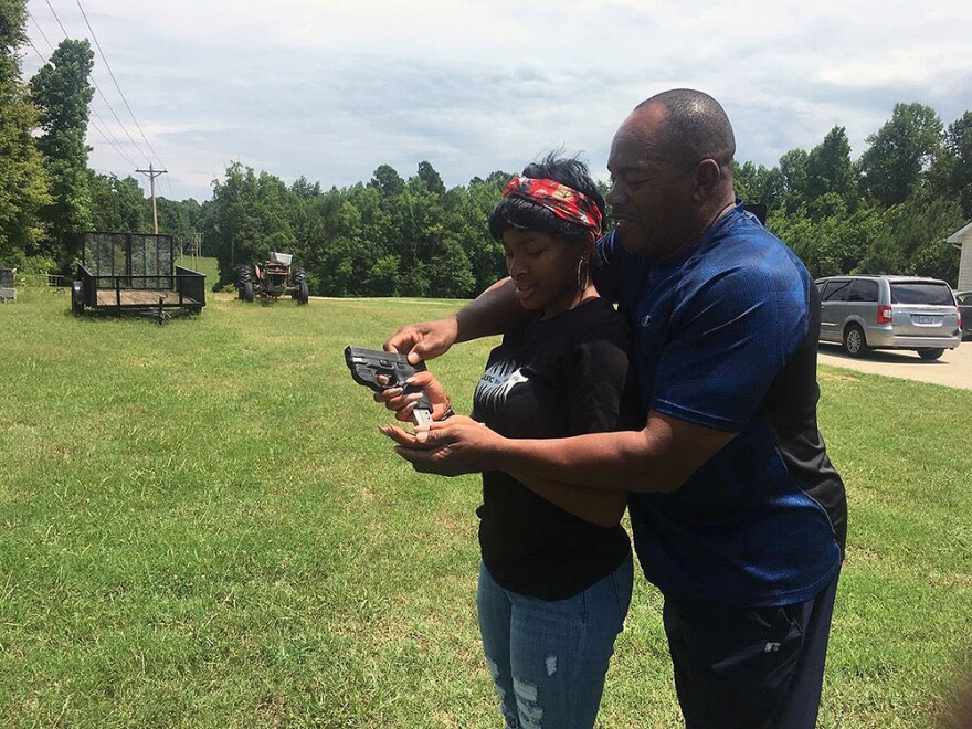 Kenzi Patrick with her grandfather James Patrick, who is teaching her how to safely reload a 9mm pistol on July 7, 2018.