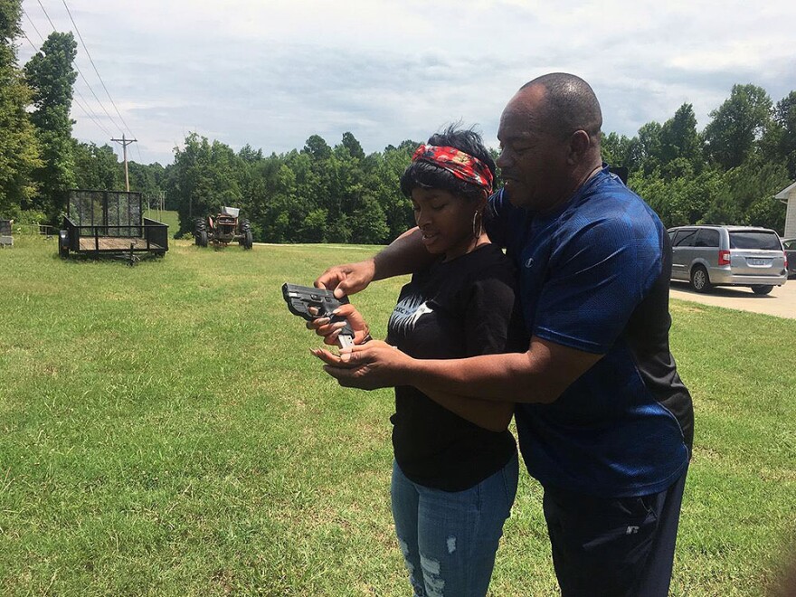 Kenzi Patrick with her grandfather James Patrick, who is teaching her how to safely reload a 9mm pistol on July 7, 2018.