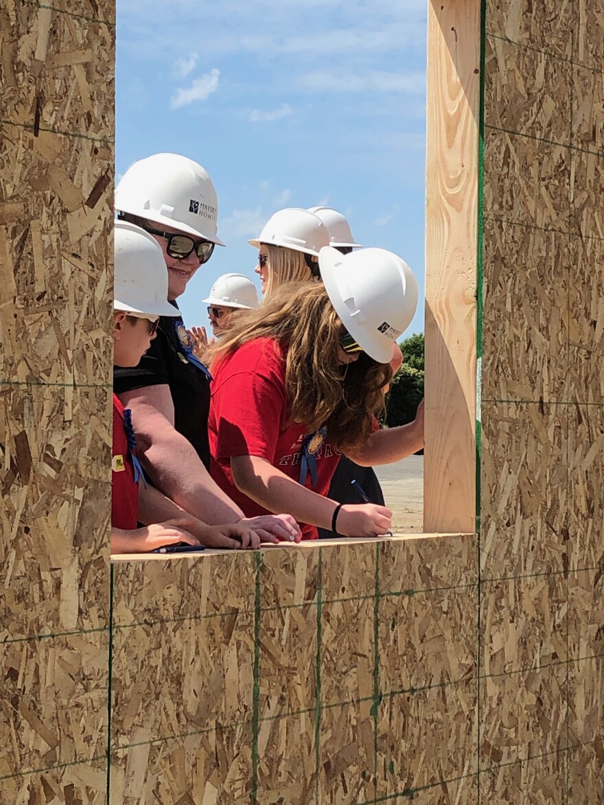 Amanda Cole (red shirt next to her sons) signs her name in her new house.