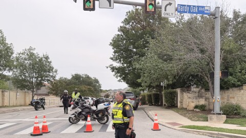 San Antonio police officers block access to Hardy Oak Boulevard near Red Hawk Ridge during a June 19, 2026, standoff in the Stone Oak area. SAPD says a domestic violence shooting left two people dead and an officer wounded.