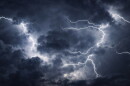 Powerful lightning bolts cutting through dark storm clouds in a night sky, capturing intense weather, atmospheric energy, and a severe thunderstorm.