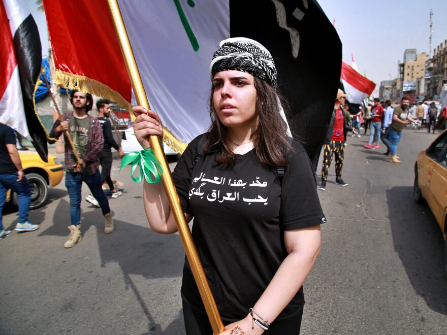 A woman holds an Iraqi flag and wearing a T-shirt with Arabic that reads, "No one in this world loves Iraq as much as I do," during a rally demanding women's rights in Tahrir Square in Baghdad, Iraq, Sunday.