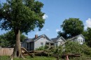A large tree lays on the lawn in front of a stately home.