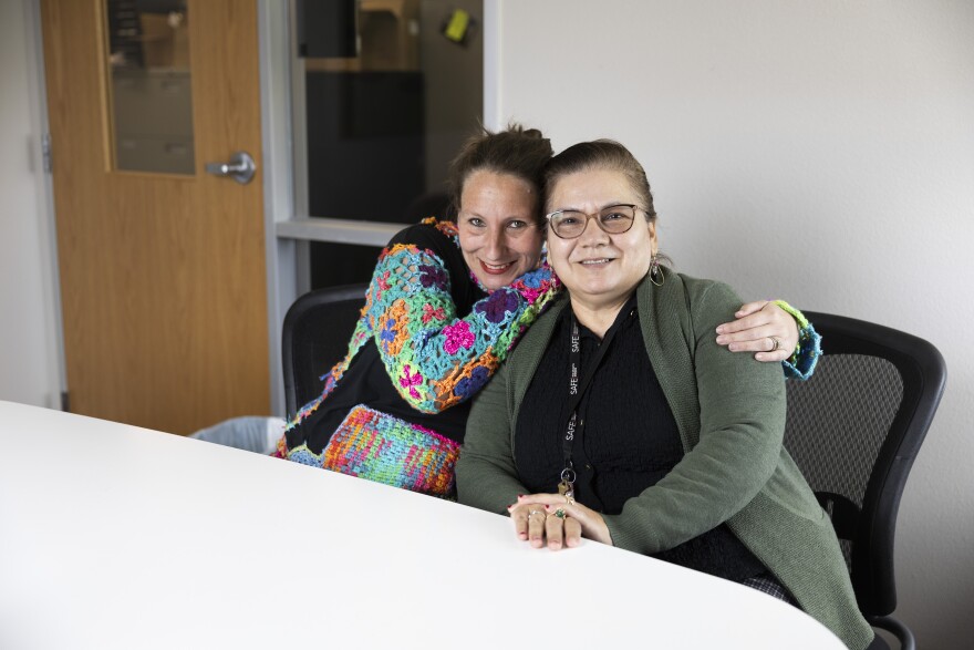 Makani Couk, left, and Elia Mondragon sit together and smile for a photo in a conference room.