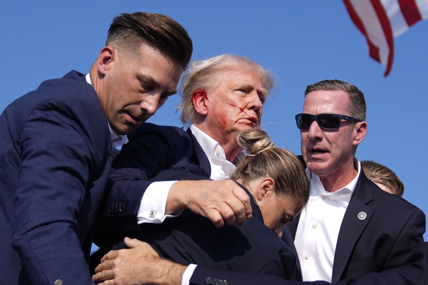 Republican presidential candidate former President Donald Trump gestures as he is surrounded by U.S. Secret Service agents at a campaign rally, Saturday, July 13, 2024, in Butler, Pa.