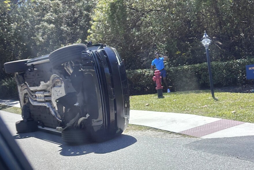 Golfer Tiger Woods stands by his overturned vehicle in Jupiter Island, Fla., on Friday, March 27, 2026.