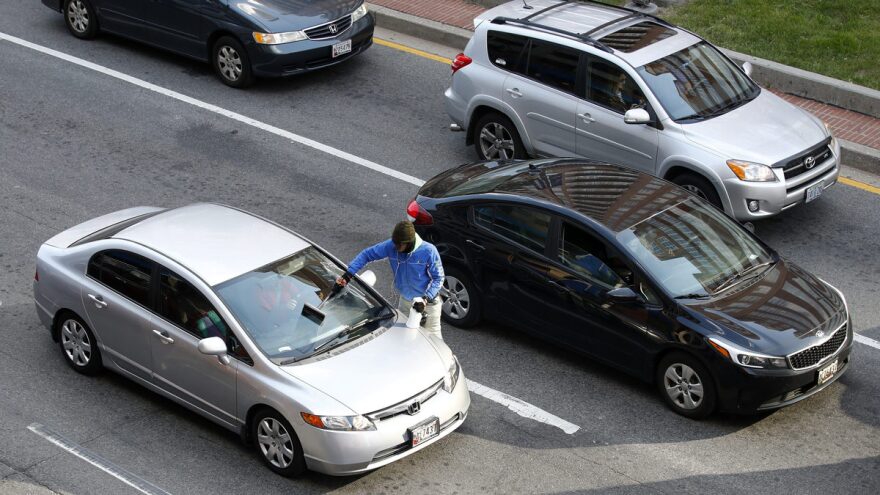 A young man washes a windshield as motorists wait at a red light in October in Baltimor