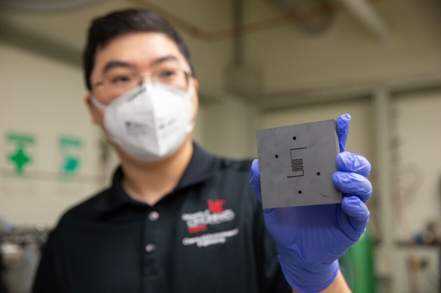 UC chemical engineer Jingjie Wu holds up the reactor where a catalyst converts carbon dioxide into methane. UC's research makes him optimistic that scientists will be able to remove carbon dioxide from the atmosphere.