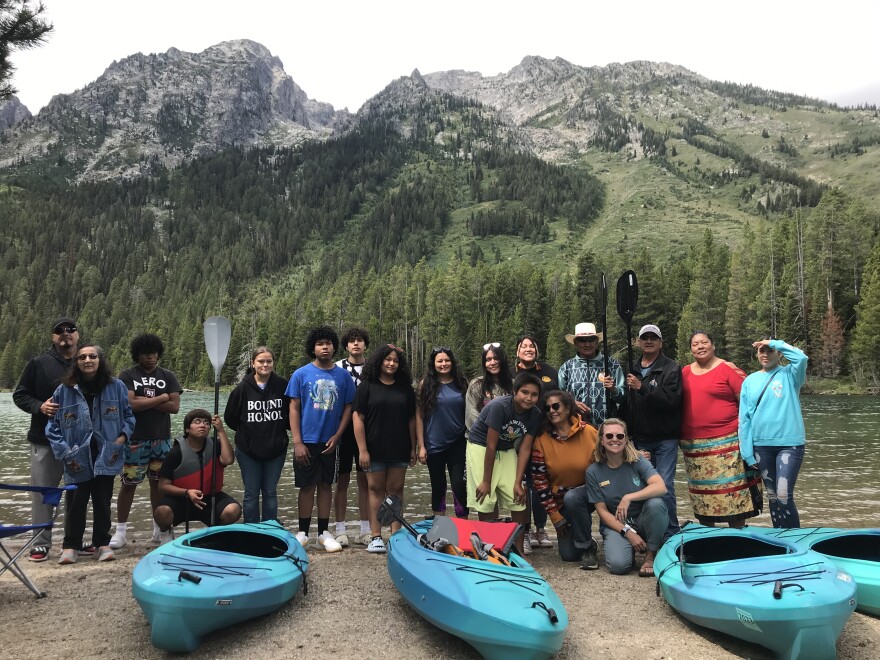 Members of the Indigenous Youth Voices youth group, tribal elders and teachers pose with kayaks at String Lake in Grand Teton National Park.