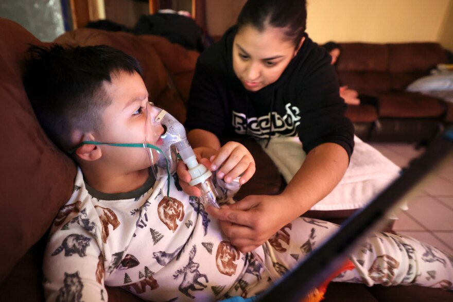 Rosa Mandujano reattaches part of her son Ruben Mandujano’s nebulizer after he pulled it off prematurely hoping he was done, at their home near the Salton Sea and Mecca, California, on Thursday, Dec. 14, 2023. Ruben, 5, has asthma and is autistic. He doesn’t like the nebulizer, which administers albuterol, as it often makes him throw up.