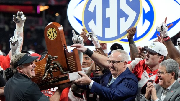 FILE - Georgia head coach Kirby Smart is handed the SEC trophy by Commissioner Greg Sankey as the team celebrates after a Southeastern Conference championship NCAA college football game against Alabama, Dec. 6, 2025, in Atlanta. (AP Photo/Mike Stewart, File)