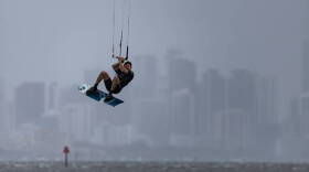 A kite boarder catches waves as rain makes its way over Brickell as seen from Matheson Hammock Park on Tuesday, April 11, 2023, in Coral Gables, Fla. 

