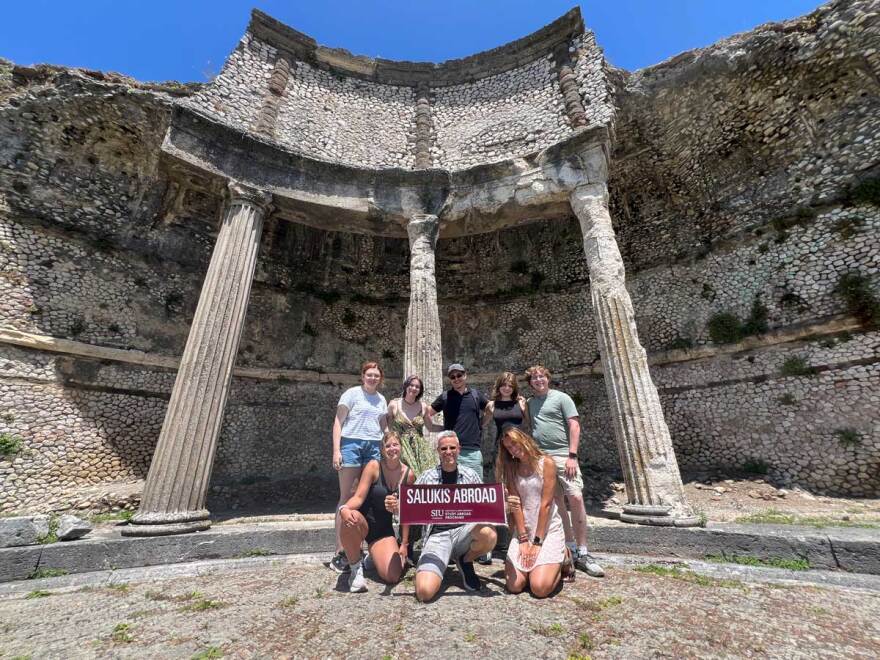 Salukis Abroad group poses in front of ancient Roman ruins.
