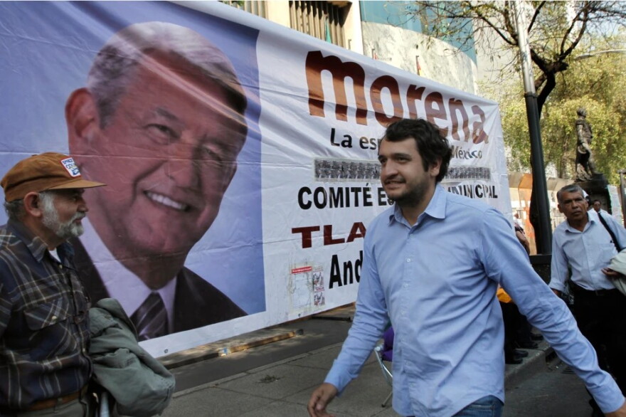 Andres Lopez Beltran, center, walks past a banner featuring an image of his father, Andres Manuel Lopez Obrador, in Mexico City, Dec. 6, 2013.