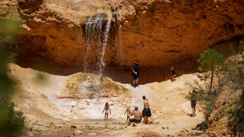 Visitors cool off under a waterfall at Utah’s Bryce Canyon National Park, Aug. 19, 2025.