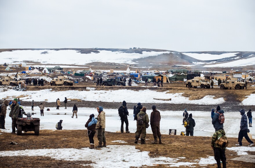 Protestors stand on the southern bank of the Cannonball River, on reservation land, as police secure the remainder of the Oceti Sakowin camp on the opposite bank.