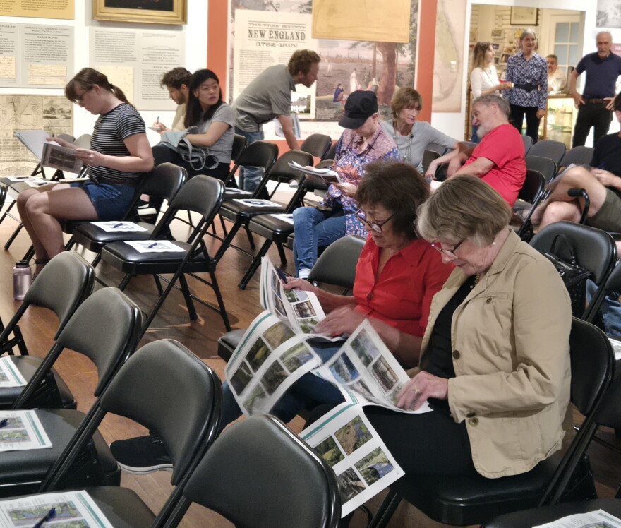 Two women discuss renders as people find their seats at the Matheson History Museum on Sept. 29. The packets include design options for the future site.