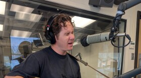 Dustin Brown playing an acoustic guitar while performing in the KETR Studios