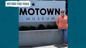A woman wearing sunglasses smiles next to the Motown Museum sign.