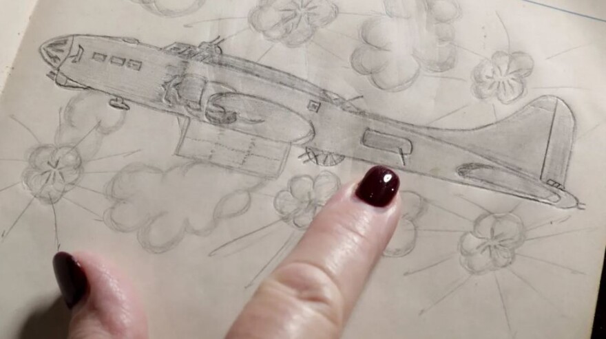 Diana Halstead shows a drawing by her father, Gene Maul, of his bomber flying through antiaircraft fire. She points out the position he manned as a waist gunner.