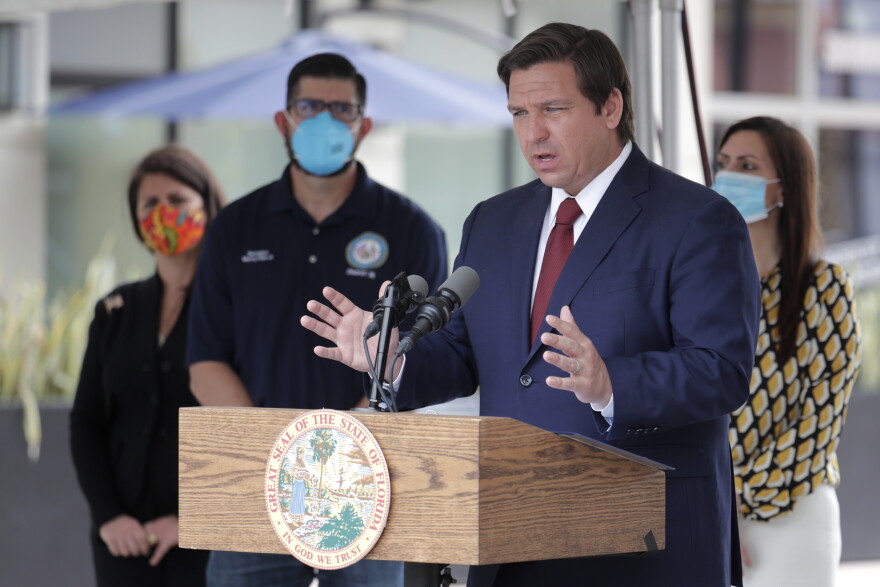 Florida Gov. Ron DeSantis, right, speaks at a news conference during the new coronavirus pandemic, Thursday, May 14, 2020, in Doral, Fla. DeSantis has signed an executive order for the reopening of Miami-Dade and Broward counties on May 18.