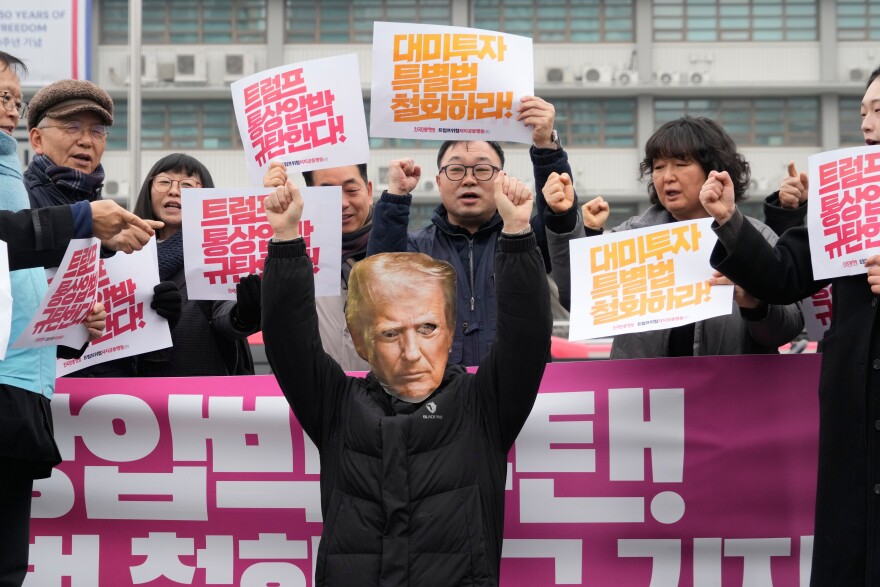 A South Korean protester, wearing a mask of U.S. President Donald Trump, gestures during a rally against Trump's tariffs policy on South Korea, near the U.S. embassy in Seoul, South Korea, Wednesday, Feb. 11, 2026. The banners, in red, read "We condemn Trump's trade pressure." (AP Photo/Ahn Young-joon)