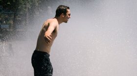 A man cools off in the Salmon Street springs fountain in Portland, Oregon as a heatwave moves over much of the United States.