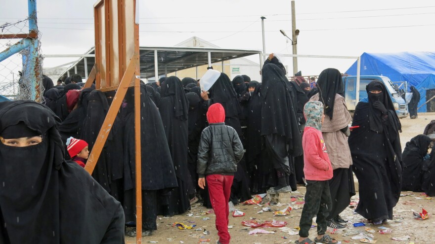 Women and children wait for distribution of food at the al-Hol camp in northeastern Syria. Most are family members of ISIS fighters, viewed by the region's Kurdish Syrian leadership as a potential danger. Iraq says it wants to bring back 30,000 of its citizens to place in Iraqi camps, but few are willing to return.