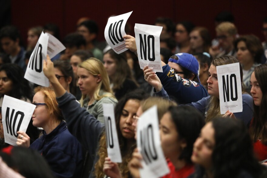 UT students raise signs signifying their opposition to university leadership during a town hall event on sexual misconduct policies in January. 