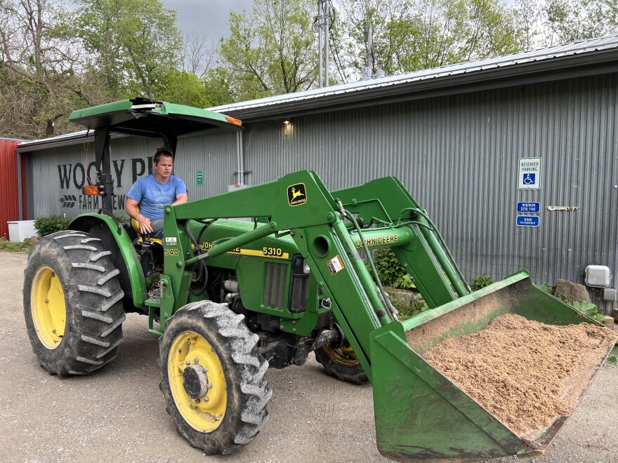 An employee loads up a tractor with spent grain to take to the pig pasture at Wooly Pig Farm Brewery.
