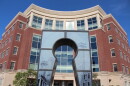 A photo of the exterior of the red brick Columbia government building. The key hole sculpture in front of the building is centered in the image. 
