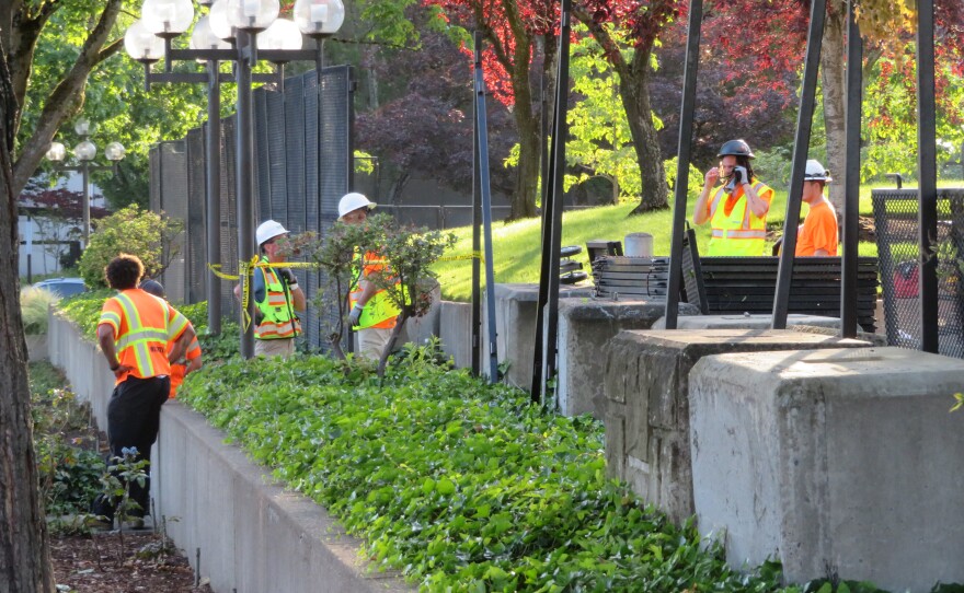 Workers taking apart fence. 