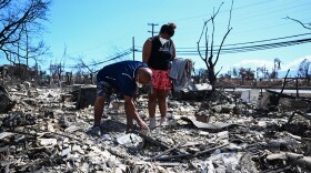 Davilynn Severson and Hano Ganer look for belongings through the ashes of their family's home on Friday in the aftermath of a wildfire in Lahaina, in western Maui, Hawaii.