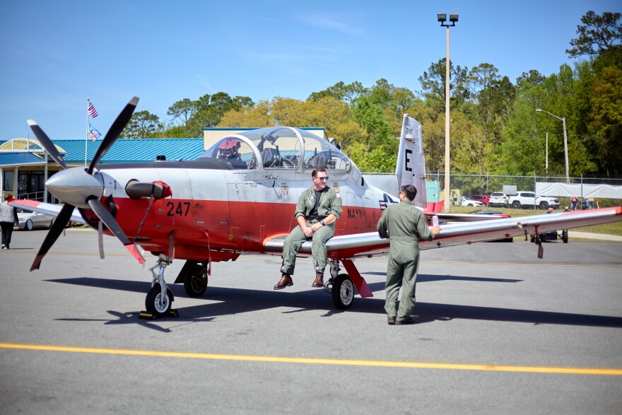 Two military pilots having a conversation while sitting on top of a North American T-6B Texan II aircraft at the University Air Center in Gainesville, Florida, March 22, 2025. (Candy Fontana Verde/WUFT News)
