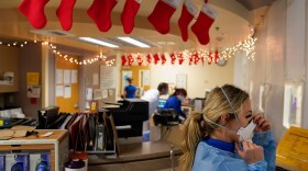 A few days before last Christmas, a registered nurse at Mission Hospital in Mission Viejo puts on her safety equipment before entering a room to check on a patient in a COVID-19 unit decorated with Christmas stockings.