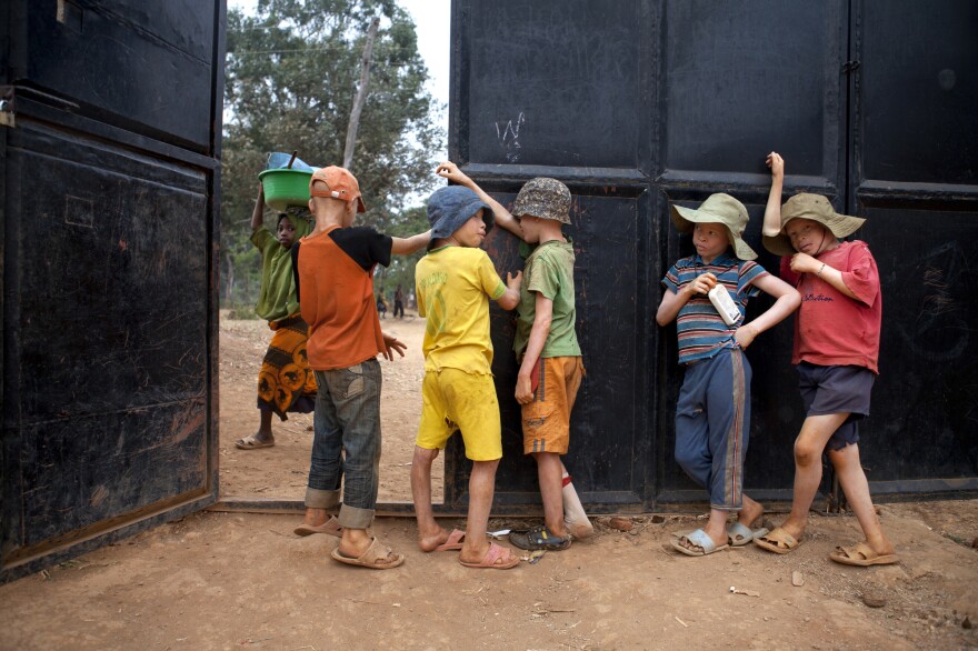 Boys hang out by the gate guarding the Kabanga Protectorate Center, as a local village girl walks by outside, in Kabanga, Tanzania.