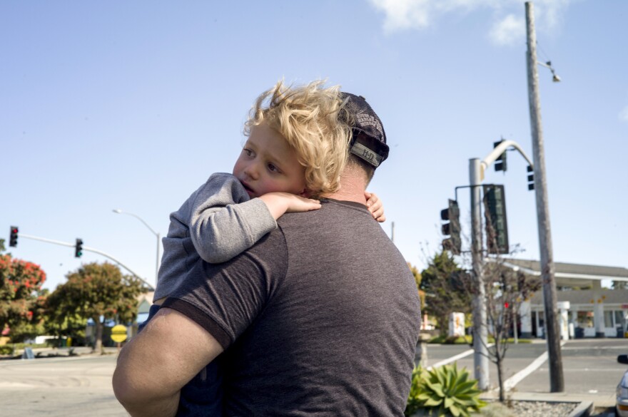 Skelton holds his son, Dakota, on their way to the grocery store.