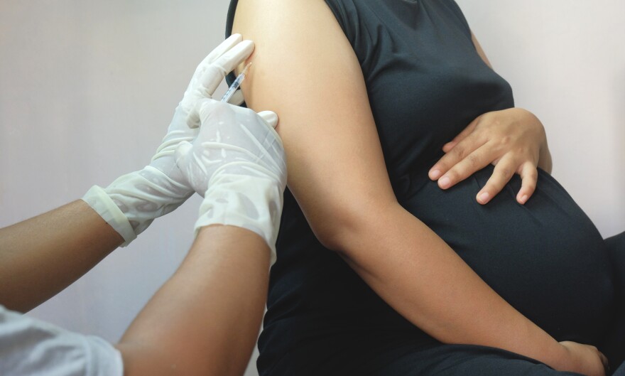 A medical professional administering a vaccine to a pregnant woman