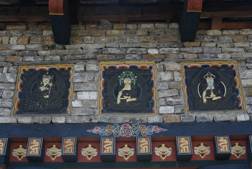 A triptych depicts Lord Buddha (middle), Guru Rinpoche, known as the Second Buddha (left), and Zhabdrung Ngawang Namgyel (right), who unified Bhutan and whose title translates as "at whose feet one submits." The work is painted above the door of the National Memorial Stupa, a Tibetan-style temple in Bhutan's capital city Thimphu.