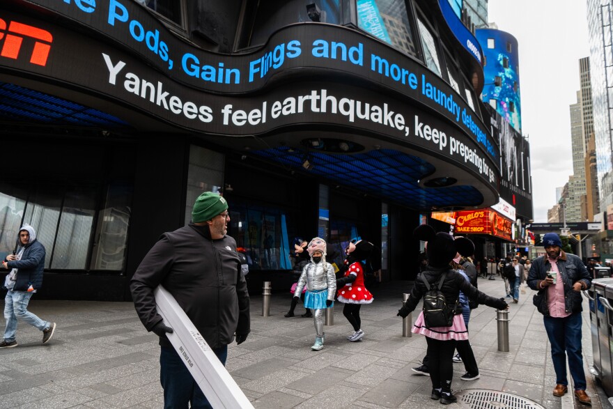 People walk around Times Square as news tickers mention the East Coast earthquake on Friday April 5, 2024 in New York. Officials say an earthquake with a preliminary magnitude of 4.8 shook the densely populated New York City metropolitan area. Residents reported they felt rumbling across the Northeast on Friday morning. The quake was centered in New Jersey about 45 miles west of New York City and 50 miles north of Philadelphia.