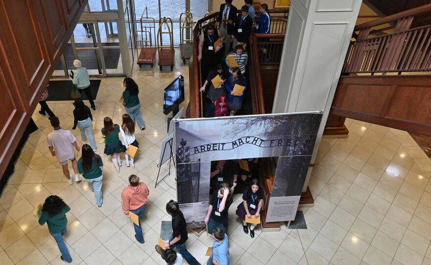 Students walk under an arch that reads 'Work sets you free,' a German phrase that was posted at entrances of concentration camps.