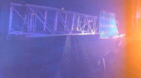 A large highway sign lies across the median on state Route 520 after a construction crane knocked it down. The sign struck a bus, injuring several people.